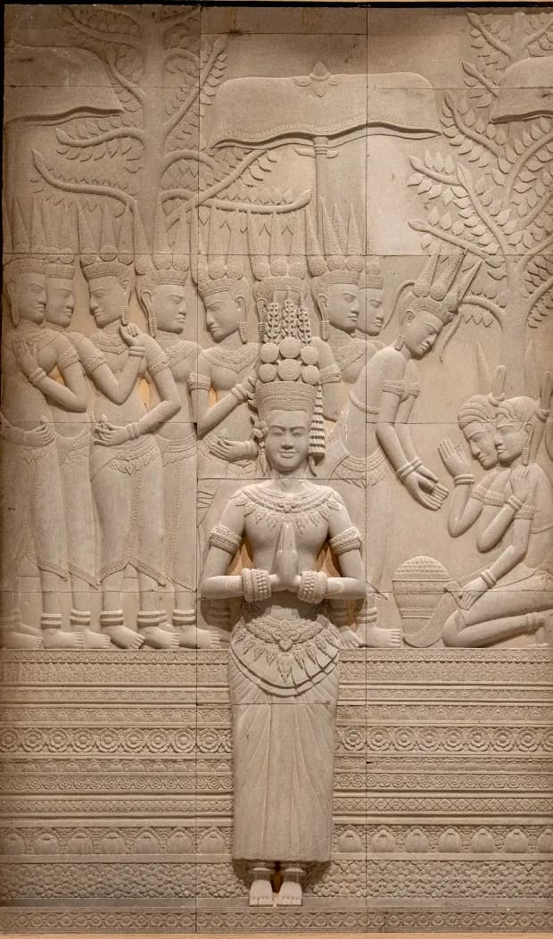 A carved stone relief of a standing figure among many others