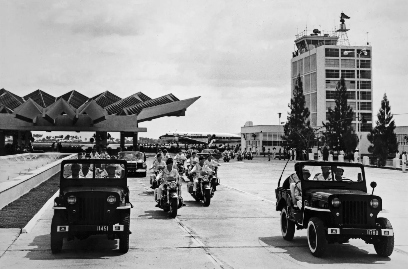 A motorcade of jeeps and motorcycles in front of the terminal