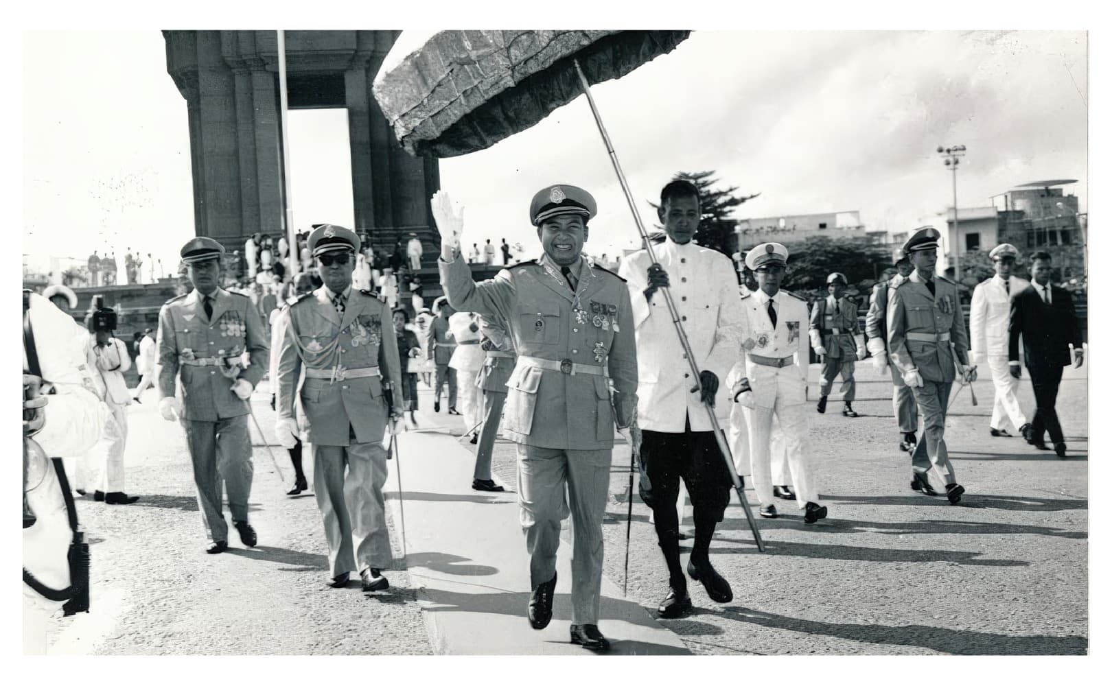 Archival black-and-white photograph of a royal procession on foot, led by men in uniform