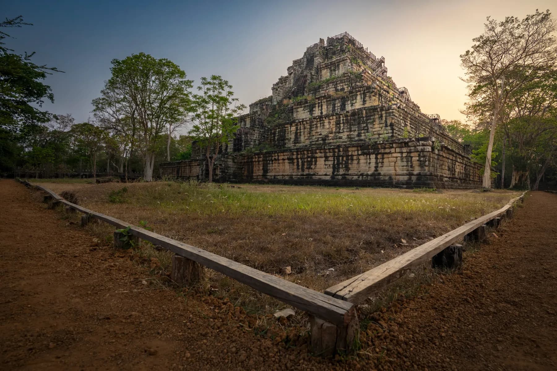 The stepped pyramid of Koh Ker at dusk, a wooden walkway crossing the clearing before it